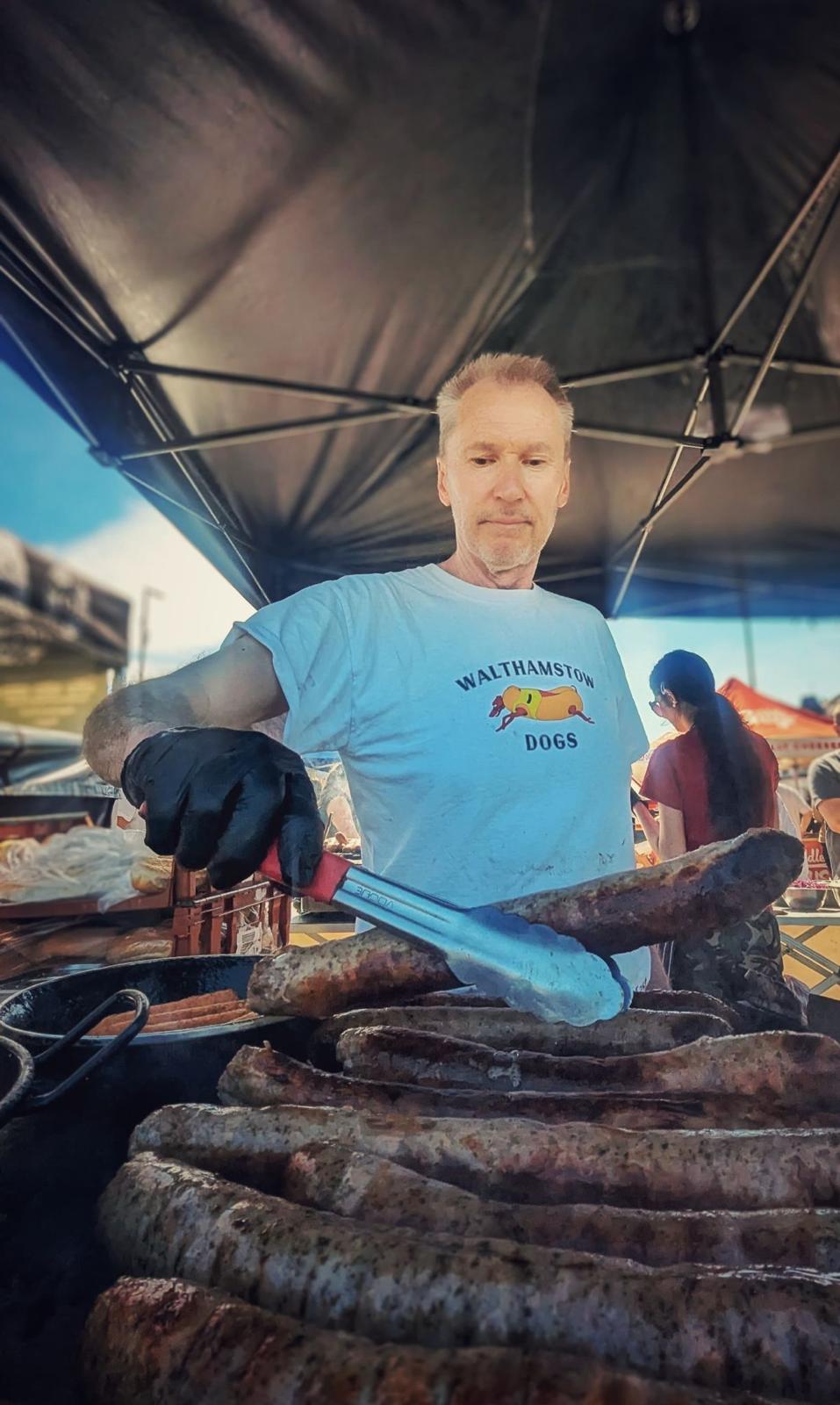 Chef turning large sausages on the grill