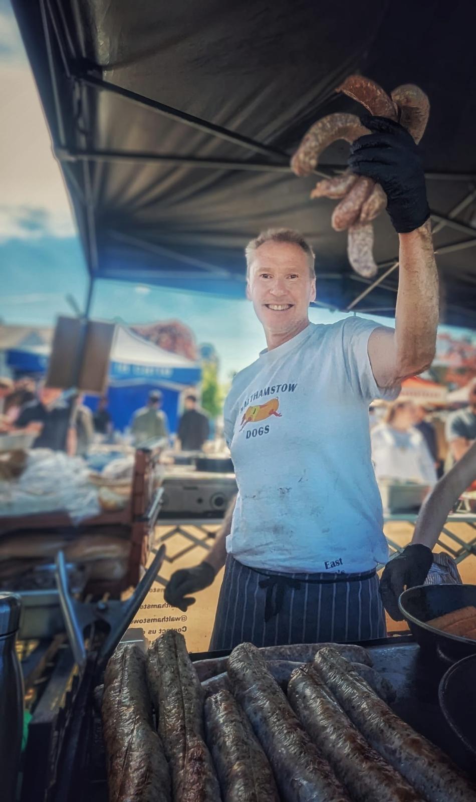 Chef holding sausages at a busy event