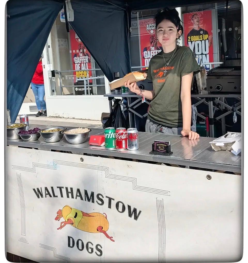 Walthamstow Dogs team member serving a hot dog from the stall in East London