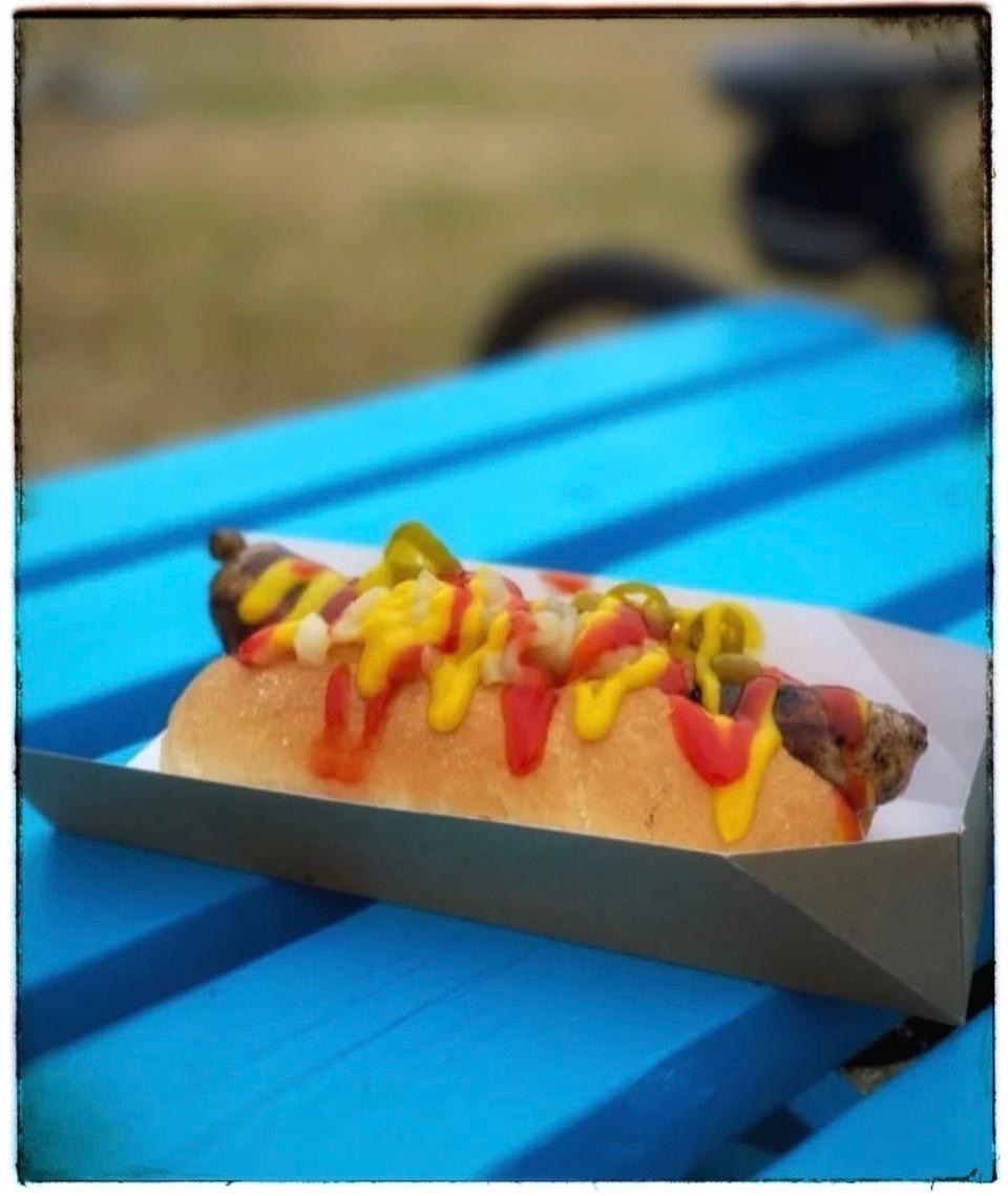 Loaded hot dog on a picnic table at an outdoor festival